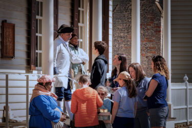 Williamsburg, Virginia, USA - March 12, 2024: Tourists listen intently as a guide speaks at Colonial Williamsburg.
