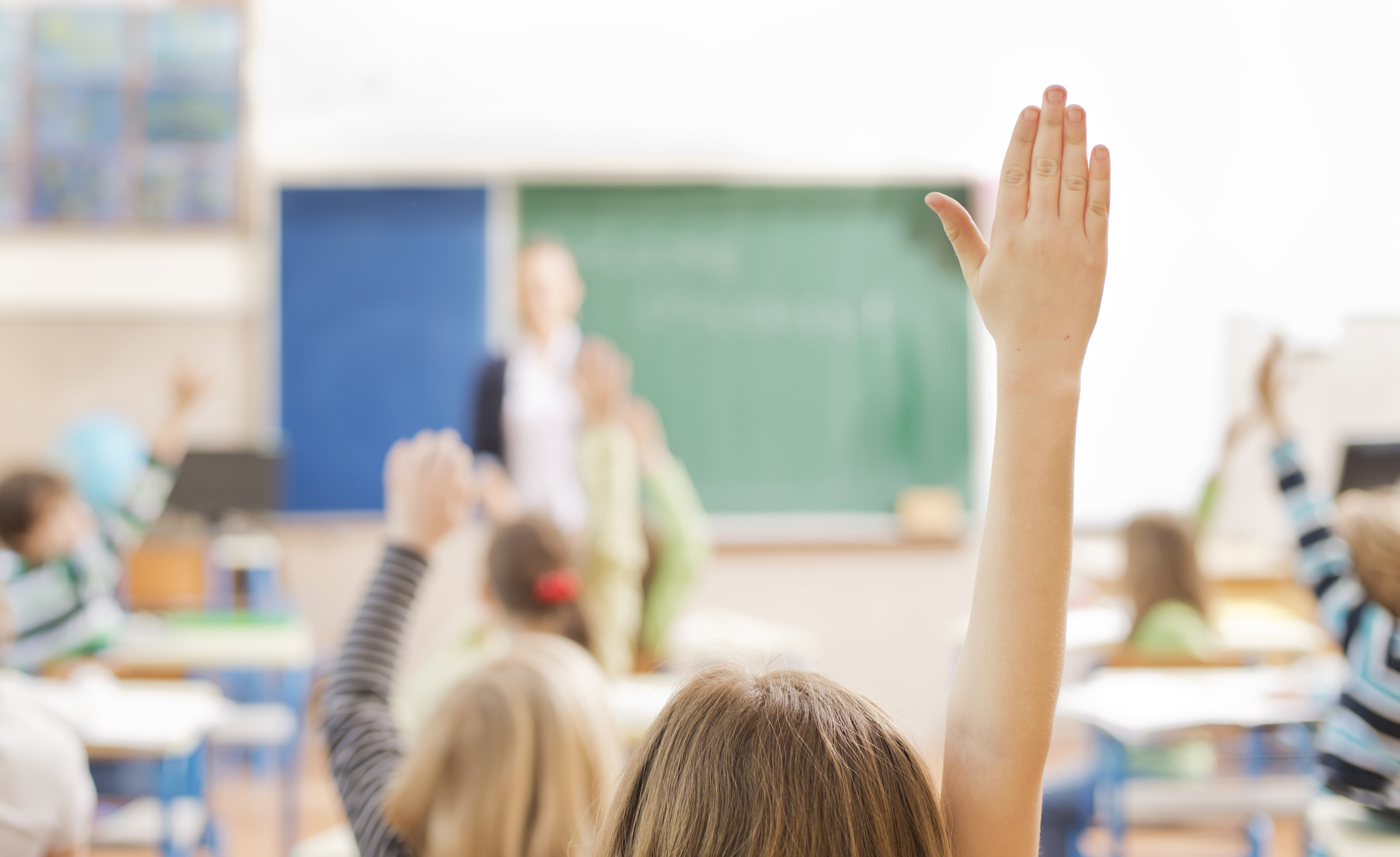 Children raising their hands in the classroom